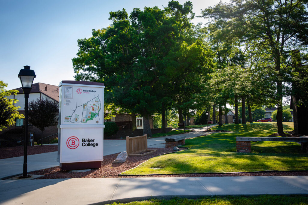 An exterior photo of the Owosso campus, including a campus map and various buildings as seen through the trees.